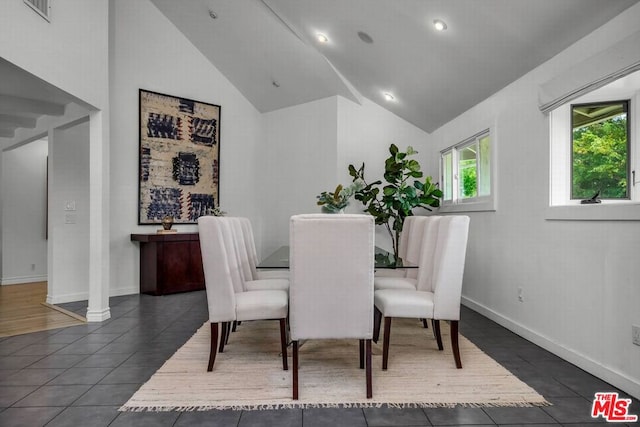 dining space with dark tile patterned flooring and high vaulted ceiling