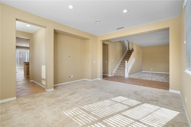 spare room with light carpet, visible vents, baseboards, stairway, and recessed lighting