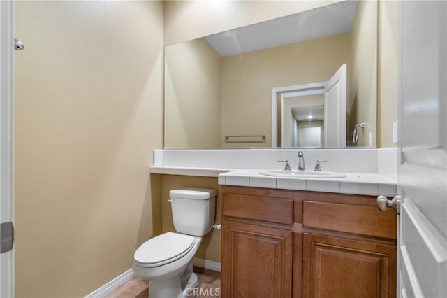 bathroom featuring baseboards, vanity, and toilet