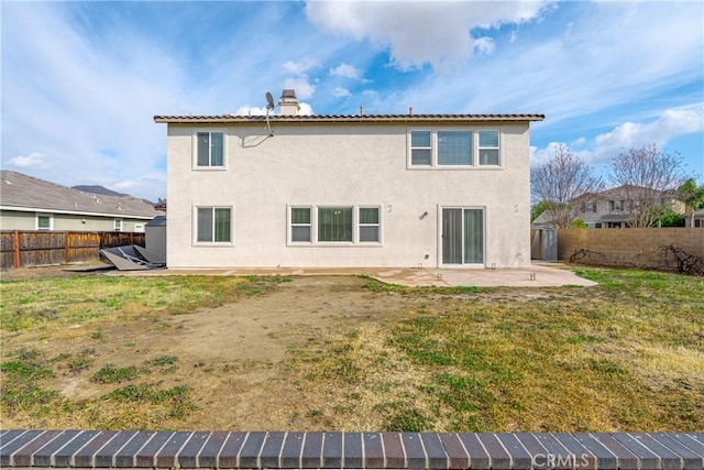 back of property featuring a patio, a fenced backyard, a yard, stucco siding, and a chimney