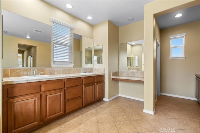 bathroom with backsplash, a sink, visible vents, and a healthy amount of sunlight