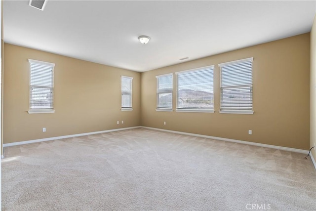 spare room with baseboards, visible vents, and light colored carpet