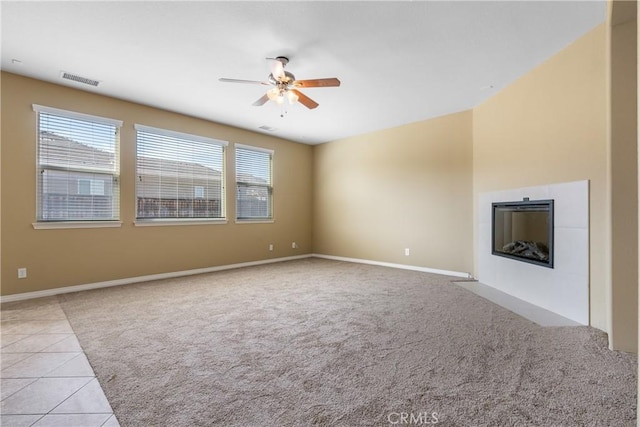 unfurnished living room with light carpet, light tile patterned floors, a fireplace with flush hearth, and visible vents