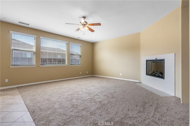 unfurnished living room with a ceiling fan, light tile patterned floors, light carpet, a fireplace, and visible vents