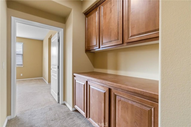 hall with baseboards and light colored carpet