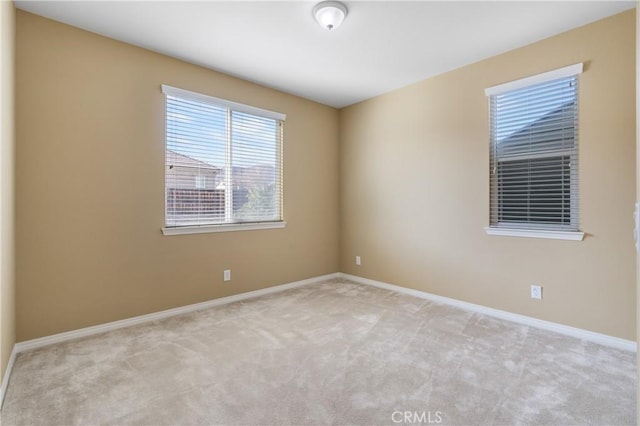 unfurnished room featuring baseboards and light colored carpet