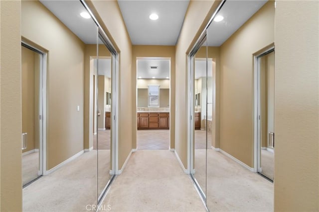 hallway featuring recessed lighting, baseboards, and light colored carpet