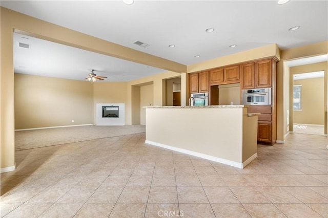 kitchen featuring stainless steel oven, ceiling fan, visible vents, and a fireplace