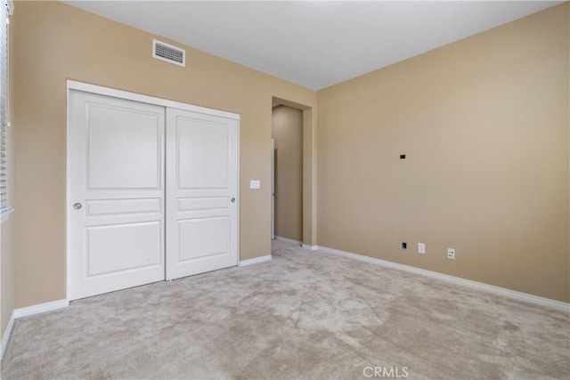 unfurnished bedroom with light carpet, a closet, visible vents, and baseboards