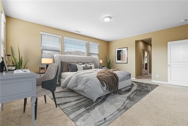 bedroom with baseboards, visible vents, and light colored carpet