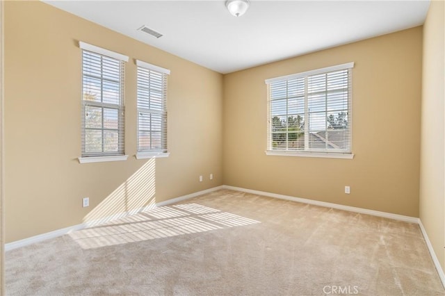 spare room featuring baseboards, visible vents, and light colored carpet