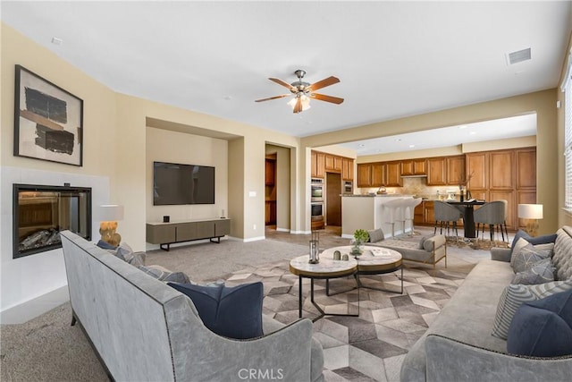 living area featuring light colored carpet, ceiling fan, baseboards, and visible vents