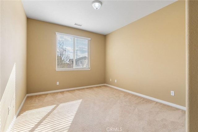 spare room with baseboards and light colored carpet