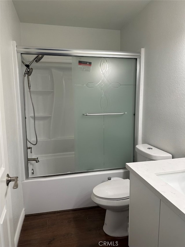 full bathroom featuring toilet, vanity, wood-type flooring, and combined bath / shower with glass door