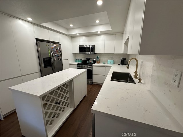 kitchen featuring a center island, a raised ceiling, sink, white cabinetry, and stainless steel appliances