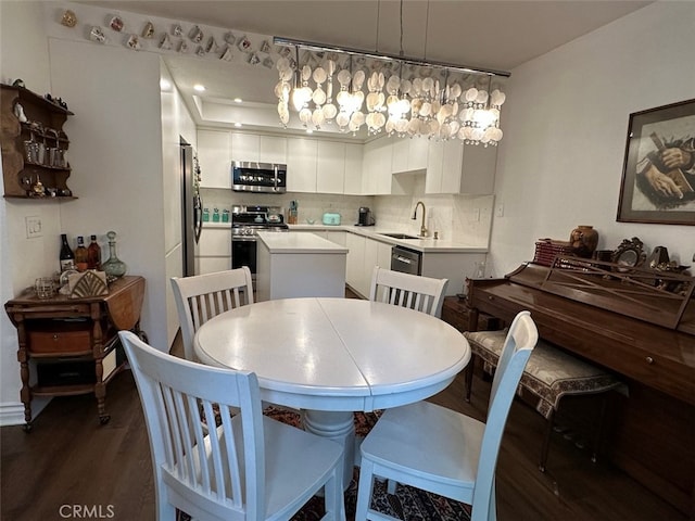 dining space featuring dark hardwood / wood-style flooring, sink, and a chandelier