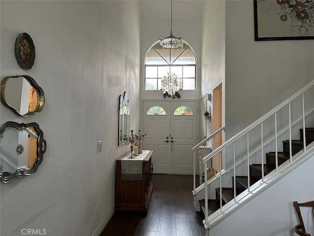 foyer entrance with a high ceiling, dark hardwood / wood-style floors, and an inviting chandelier