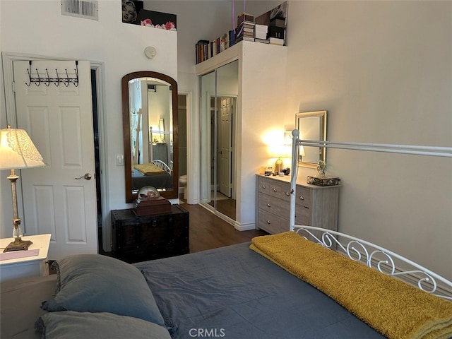 bedroom with a closet, dark wood-type flooring, and a high ceiling