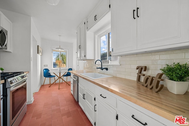 kitchen featuring sink, hanging light fixtures, stainless steel appliances, butcher block countertops, and white cabinets