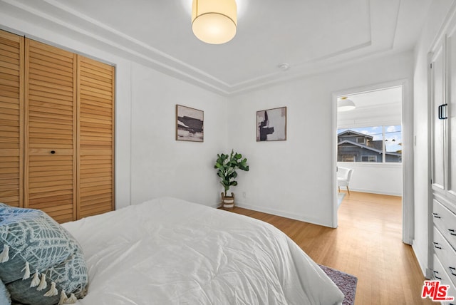 bedroom with light hardwood / wood-style floors and a closet