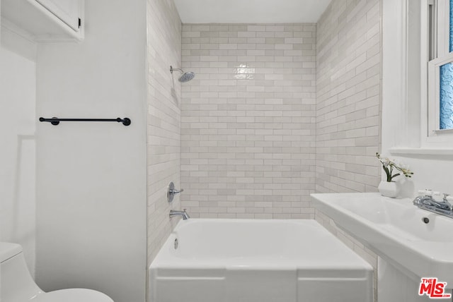 bathroom featuring toilet and tiled shower / bath