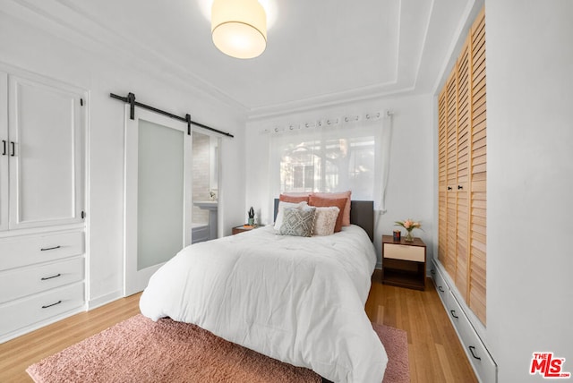 bedroom with light hardwood / wood-style floors and a barn door