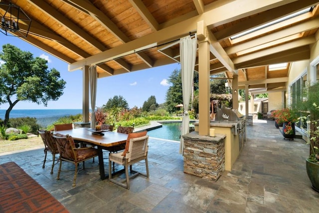 view of patio featuring an outdoor kitchen, a grill, and a water view