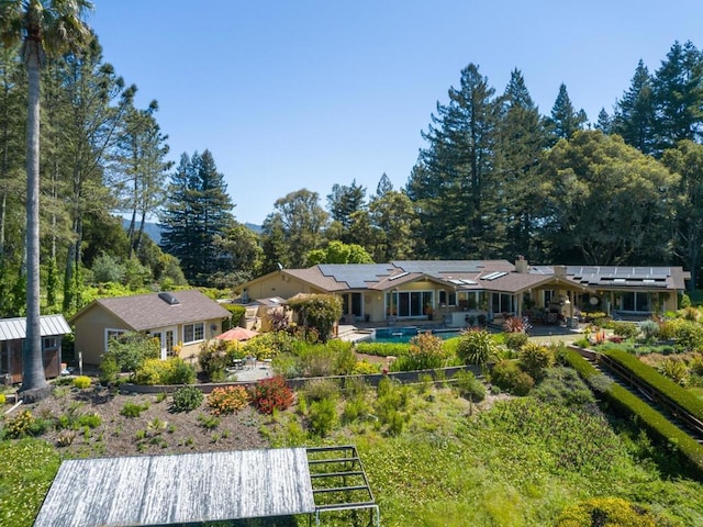 back of property with solar panels and a patio