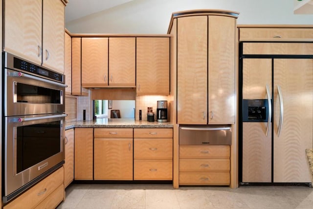 kitchen featuring decorative backsplash, lofted ceiling, stainless steel appliances, and light brown cabinetry