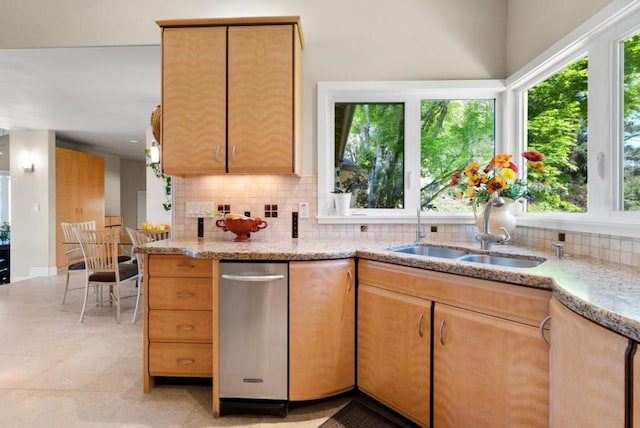 kitchen with backsplash, plenty of natural light, light stone countertops, and sink