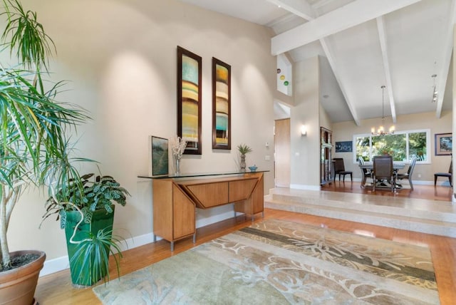 entryway with hardwood / wood-style floors, lofted ceiling with beams, and a chandelier