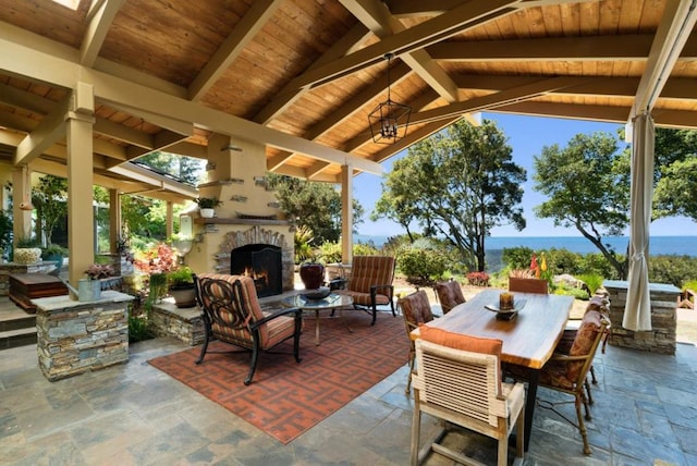 view of patio with a water view and an outdoor stone fireplace