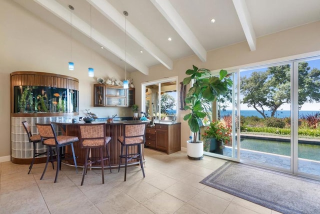 bar with pendant lighting, vaulted ceiling with beams, and a water view