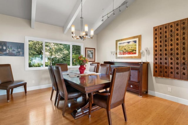 dining room featuring vaulted ceiling with beams, light hardwood / wood-style floors, and an inviting chandelier