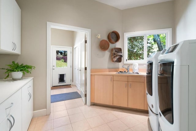 laundry area featuring washer and clothes dryer, cabinets, light tile patterned floors, and sink