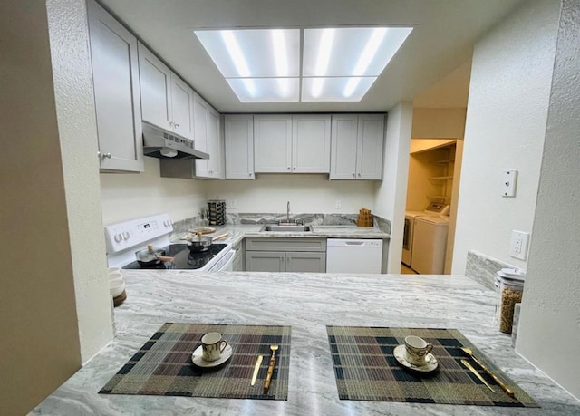 kitchen featuring washing machine and clothes dryer, sink, and white appliances