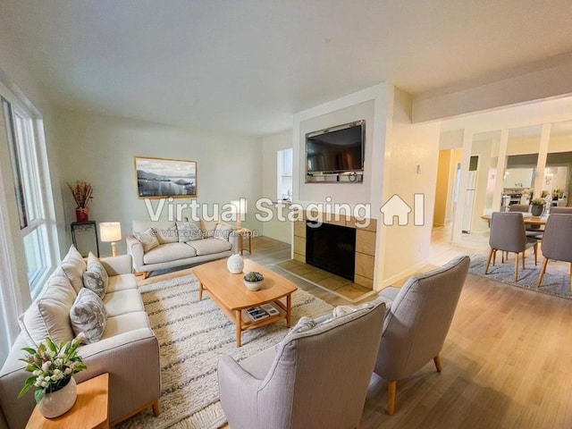 living room featuring light wood-type flooring and a tiled fireplace