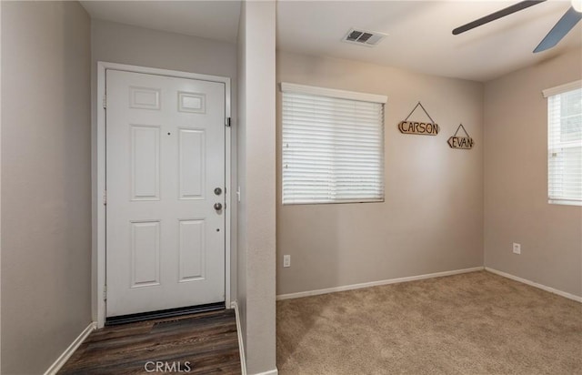 entryway featuring ceiling fan and dark colored carpet