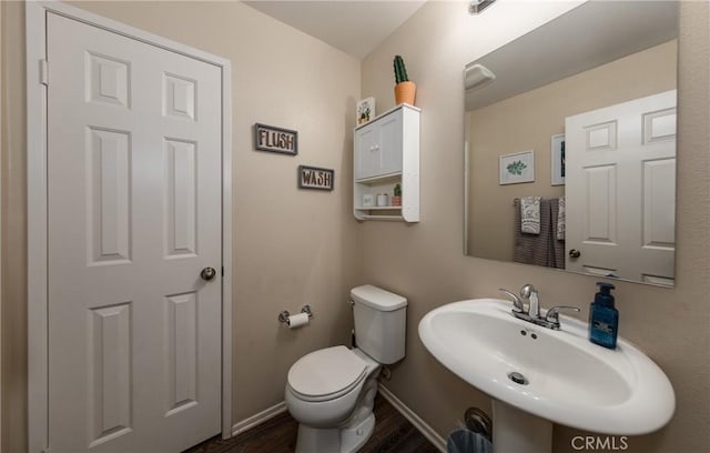 bathroom with toilet, sink, and hardwood / wood-style flooring