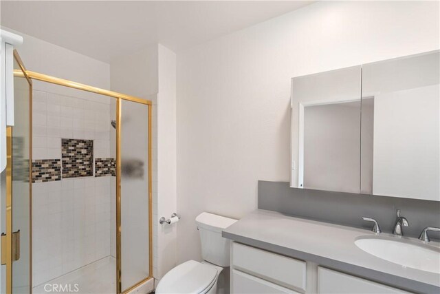 bathroom with vanity, toilet, and a shower with shower door