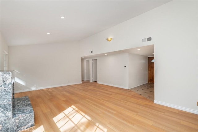 unfurnished living room with a towering ceiling and light hardwood / wood-style floors