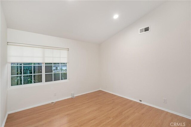 unfurnished room with light hardwood / wood-style floors and vaulted ceiling