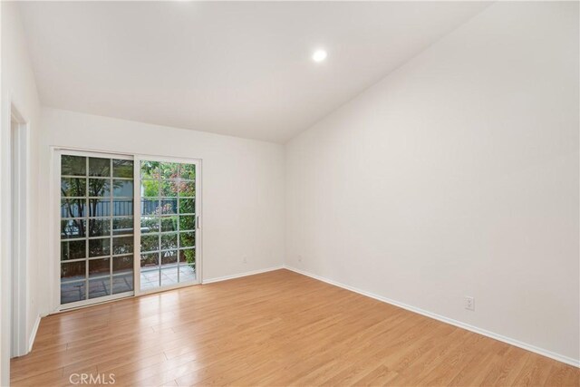 empty room featuring vaulted ceiling and light hardwood / wood-style flooring