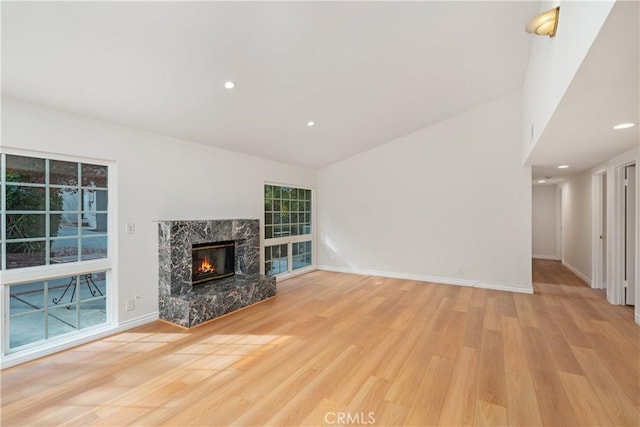 unfurnished living room featuring light hardwood / wood-style floors, a high end fireplace, and vaulted ceiling