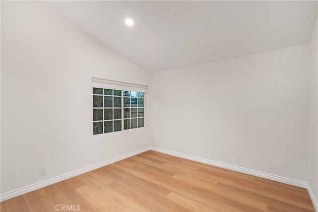 spare room with lofted ceiling and wood-type flooring