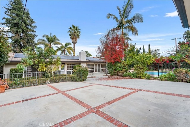 view of front of property with a fenced in pool, solar panels, and a patio area