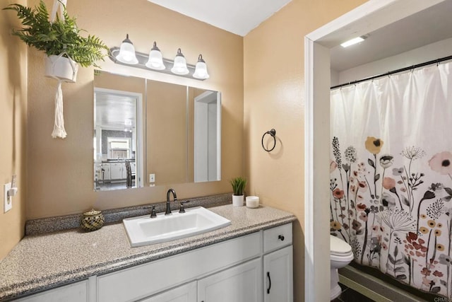 bathroom with curtained shower, vanity, and toilet