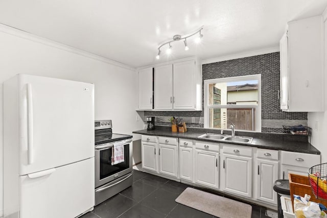 kitchen with dark countertops, stainless steel electric range oven, a sink, and freestanding refrigerator