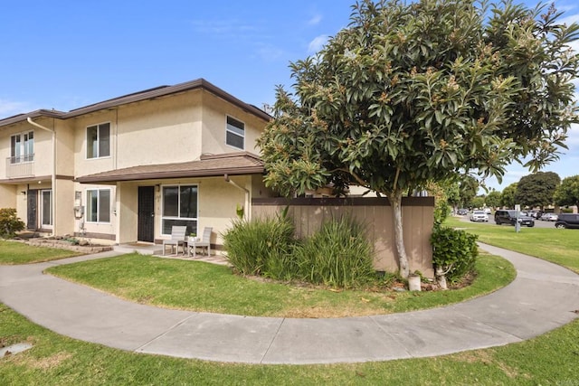 back of house featuring a lawn and stucco siding