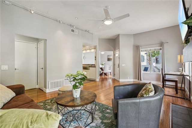 living room featuring ceiling fan, light hardwood / wood-style floors, and track lighting